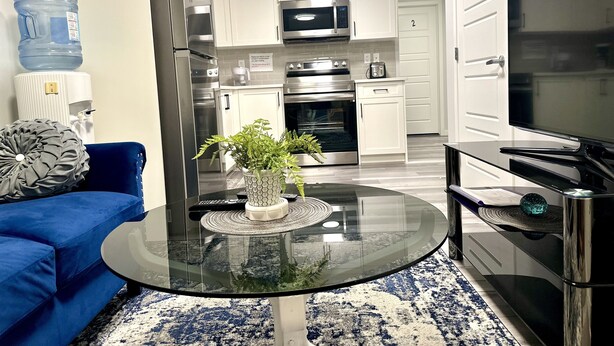 A modern kitchen with white cabinets, stainless steel appliances, and a large water dispenser. - Global Family Canada (Calgary)