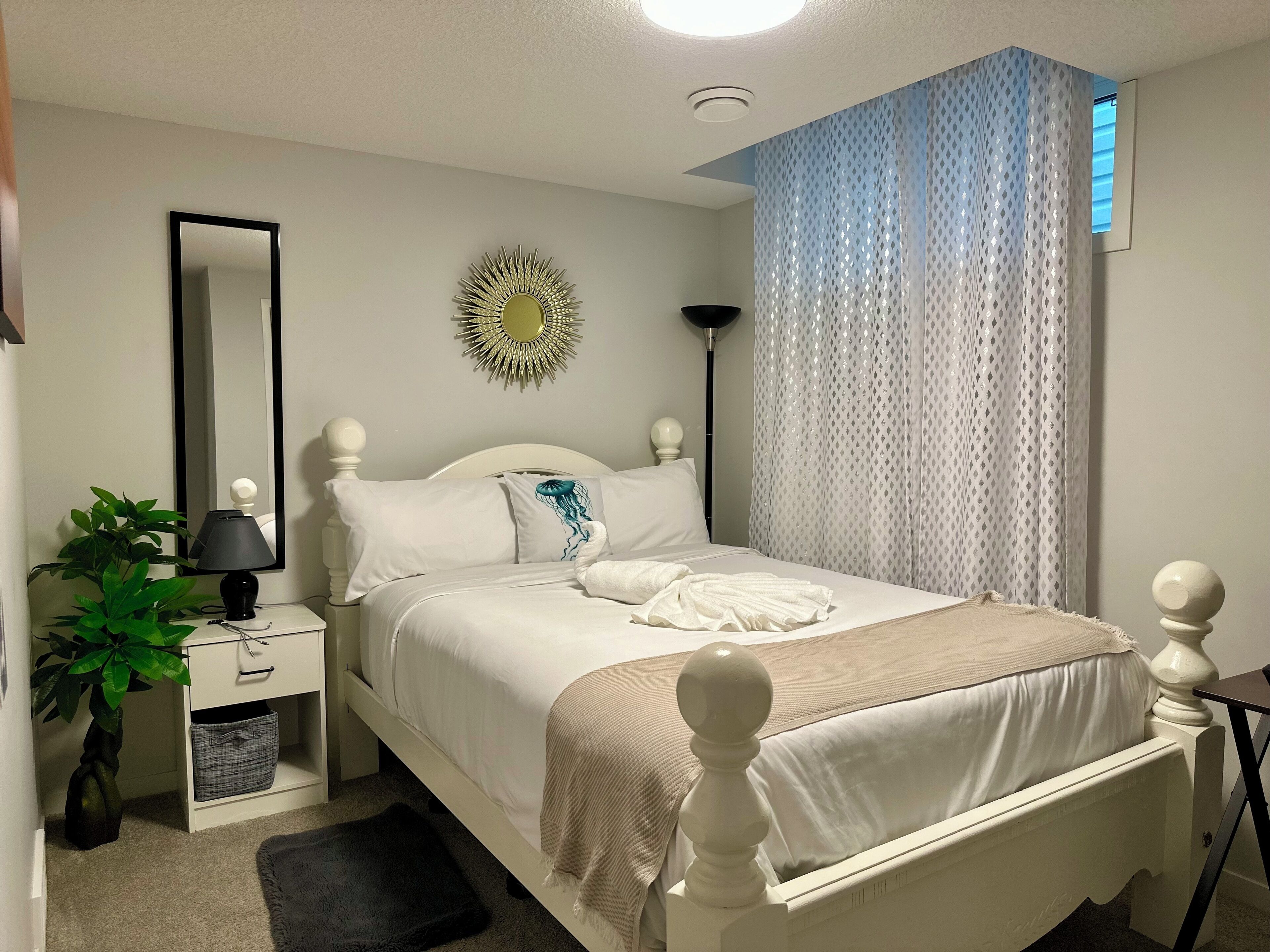 A neatly arranged bedroom with a bed, bedside table, lamp, and a potted plant.