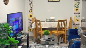 A modern living room with a TV, wooden chairs, a glass coffee table, and a welcome sign. - Global Family Canada (Calgary)