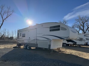 A large RV with a covered living area, a kitchen, and a bathroom.