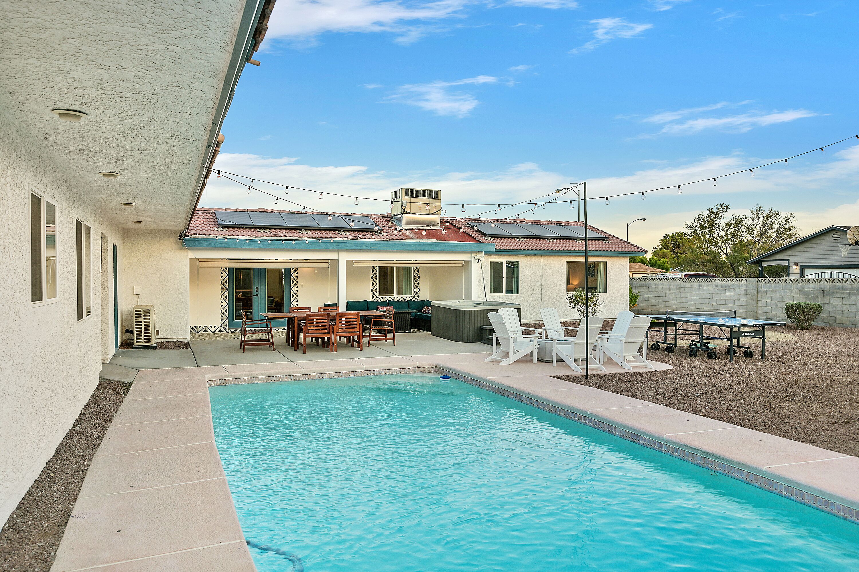 A swimming pool with a patio area, outdoor furniture, and a covered seating area.