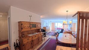 Un amplio espacio habitable con una mesa de comedor de madera, un tapete grande y vistas al exterior.