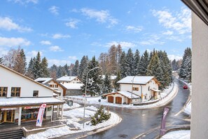 A snow-covered village with buildings, a road, and a car. - Central base for biking and skiing (Lenzerheide/Lai)
