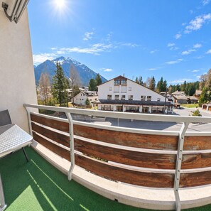 A balcony with a view of a mountain, a building with a white facade, and a clear blue sky. - Central base for biking and skiing (Lenzerheide/Lai)