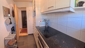 Una cocina moderna con armarios blancos, encimera negra y campana extractora de acero inoxidable.