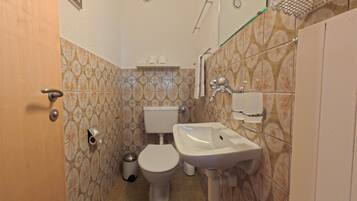 Ein Badezimmer mit Toilette, Bidet, Waschbecken und Spiegel.