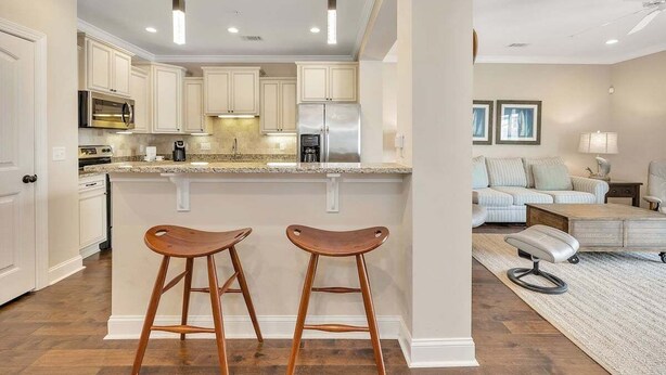 A modern kitchen with white cabinets, stainless steel appliances, and a central island with stools.