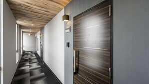 Un couloir avec un plafond en bois, une grande porte métallique et un sol à motifs.