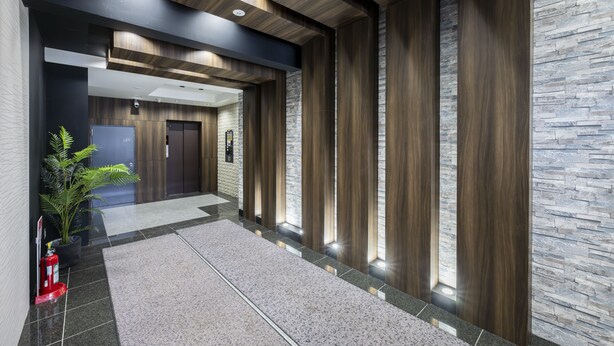 Un hall d’entrée moderne avec un mur en pierre, des lambris en bois et un extincteur.