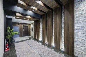 Eine moderne Lobby mit Steinwand, Holzvertäfelung und einem Feuerlöscher.