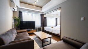 Un salon moderne avec un canapé, une table basse, un téléviseur et un grand miroir.