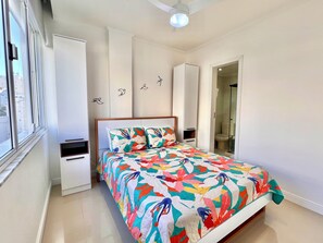 A bedroom with a bed, a wardrobe, a bedside table, a window, and a bathroom door.