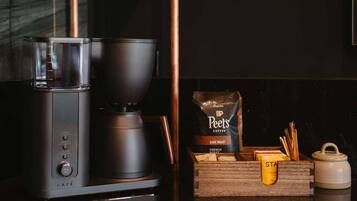 A coffee maker, Peet's Coffee bag, and a wooden box with a yellow container on a kitchen counter.