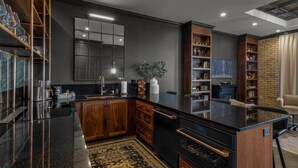A modern kitchen with dark cabinetry, a black countertop, and a built-in oven. - Perfect for Couples-Walk Everywhere-Luxe Apt (Rogers)