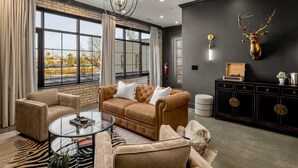A modern living room with a leather sofa, a glass coffee table, and a zebra-patterned rug. - Perfect for Couples-Walk Everywhere-Luxe Apt (Rogers)