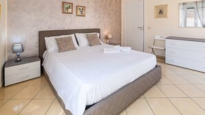 Une chambre bien rangée, avec un grand lit, des tables de chevet, une commode et une porte.