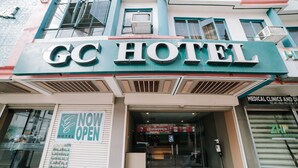 El exterior del Hotel GC con un cartel de 'Abierto ya', una entrada visible y un anuncio de clínica médica a la derecha.