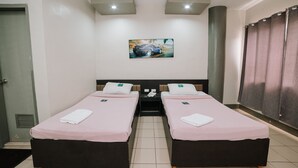 Una habitación de hotel con dos camas individuales, un cuadro en la pared y un armario.