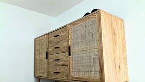 Un meuble en bois doté de tiroirs et d’un panneau en treillis, reposant sur des pieds en bois.