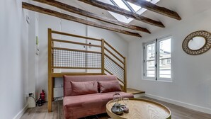 Une pièce moderne avec un escalier en bois, un canapé rose et une table ronde en bois.