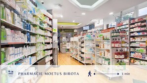Interieur van een apotheek met schappen vol producten, een apothekersbalie en een bordje met de tekst 'Servez-vous' (Zelfbediening).