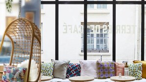 A cozy cafe interior with wicker chairs, a table set with a teapot, cups, and pastries.
