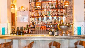 A bar area with a variety of bottles and glasses, a sign welcoming guests, and a decorative bowl on the counter.