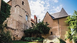 Un edificio histórico con una torre, rodeado de vegetación y un cielo despejado.