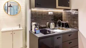 Eine kompakte Küche mit einer Mikrowelle, einem Wasserkocher und einem Toaster auf der Arbeitsfläche, einem Spülbecken und einem kleinen Schrank.