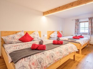A hotel room with two wooden beds, each with patterned bedding, red pillows, and towels. - Two modern holiday flats on the farm, ski-out (Itter)