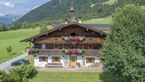 A traditional wooden chalet with a balcony, surrounded by lush greenery and mountains. - Two modern holiday flats on the farm, ski-out (Itter)