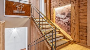 A wooden staircase with metal railings, a framed historical photo on the wall, and a sign above the stairs. - Two modern holiday flats on the farm, ski-out (Itter)