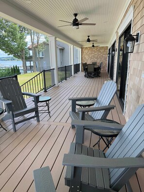 A covered outdoor deck with Adirondack chairs, a table, and ceiling fans.