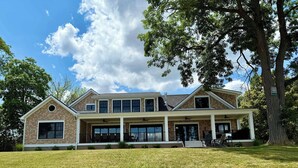 A two-story house with a large front porch, multiple windows, and a tree in the background. - NEW-Skaneateles Level Lakefront-Ready to Rent! (Skaneateles)