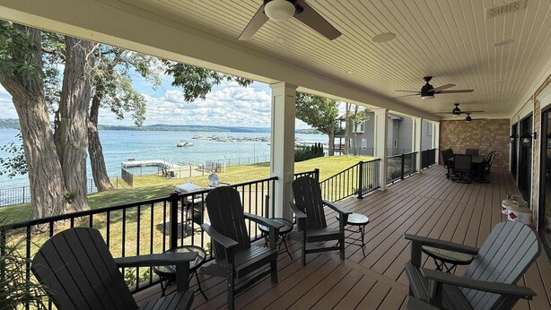 A covered deck with outdoor furniture, ceiling fans, and a view of a lake. - NEW-Skaneateles Level Lakefront-Ready to Rent! (Skaneateles)