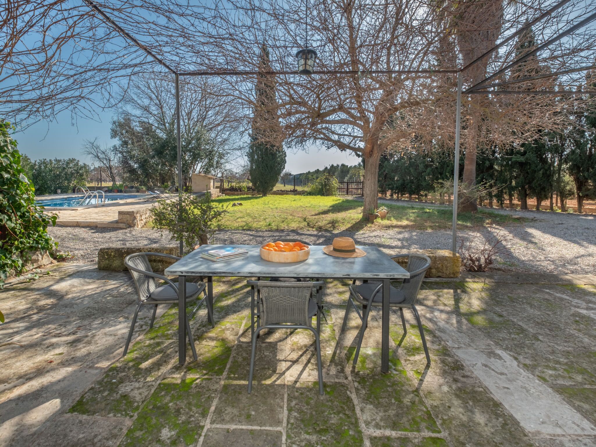 An outdoor patio with a table set for dining, surrounded by chairs.