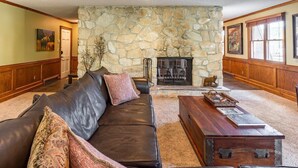 A living room with a stone fireplace, leather sofa, and wooden coffee table.