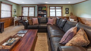 A living room with a sectional sofa, a wooden coffee table, and a bookshelf.