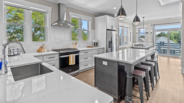 A modern kitchen with a large island, stainless steel appliances, and ample natural light from large windows.