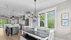 A spacious kitchen with a central island, white cabinetry, and a large dining table.