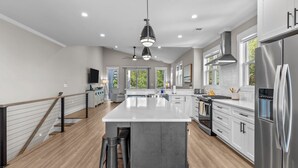 A modern kitchen with a large island, stainless steel appliances, and a ceiling fan.