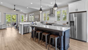 A modern kitchen with a large island, stainless steel appliances, and a view of the outdoors.