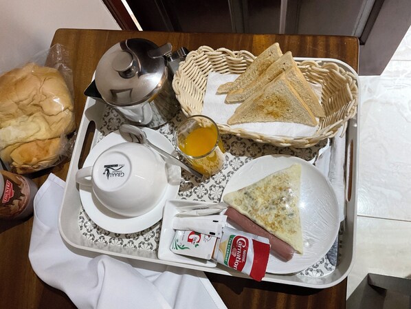 Uma bandeja com uma xícara, torradas, um cachorro-quente e um pacote de cream cheese.