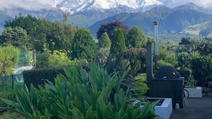 A patio with a grill and a view of snow-capped mountains. - Cosy retreat with spectacular mountain views, central to Kaikoura's attractions  (Hapuku)