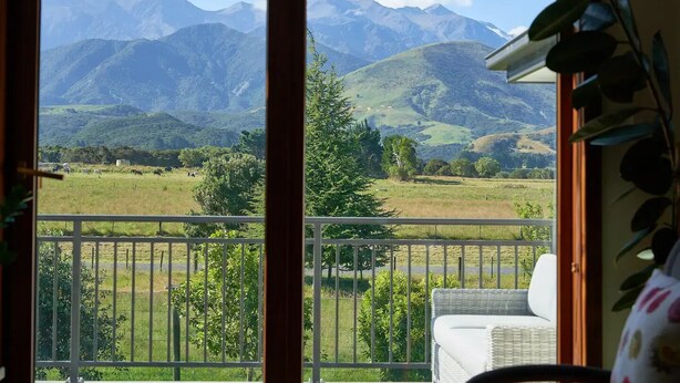 A balcony with a view of a mountainous landscape, a grassy field, and a few trees. - Cosy retreat with spectacular mountain views, central to Kaikoura's attractions  (Hapuku)