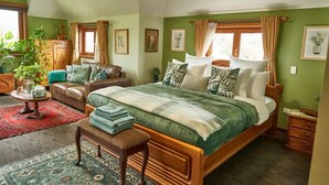 A spacious bedroom with a large bed, a wooden bench, a small table with a vase, and a green wall. - Cosy retreat with spectacular mountain views, central to Kaikoura's attractions  (Hapuku)