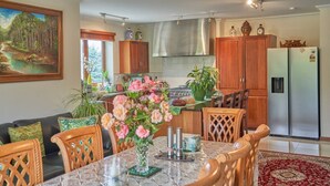 A modern kitchen with wooden cabinets, stainless steel appliances, and a dining area with a table and chairs. - Cosy retreat with spectacular mountain views, central to Kaikoura's attractions  (Hapuku)