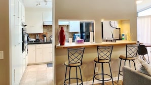 A compact kitchen with a central island, bar stools, and a dining area with a sofa. - Amazing and centrally located summer oasis with a Mid-century modern feel (Austin)