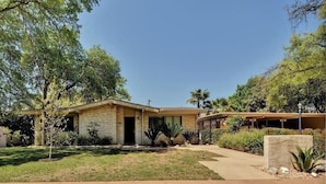 A single-story house with a brick facade, a front porch, and a well-maintained lawn. - Amazing and centrally located summer oasis with a Mid-century modern feel (Austin)