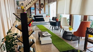A modern hotel lobby with a staircase, seating area, and reception desk. - Cohouse (Bawal)